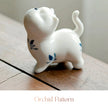 Close-up of a white ceramic Spirit Cat figurine with a blue orchid pattern
