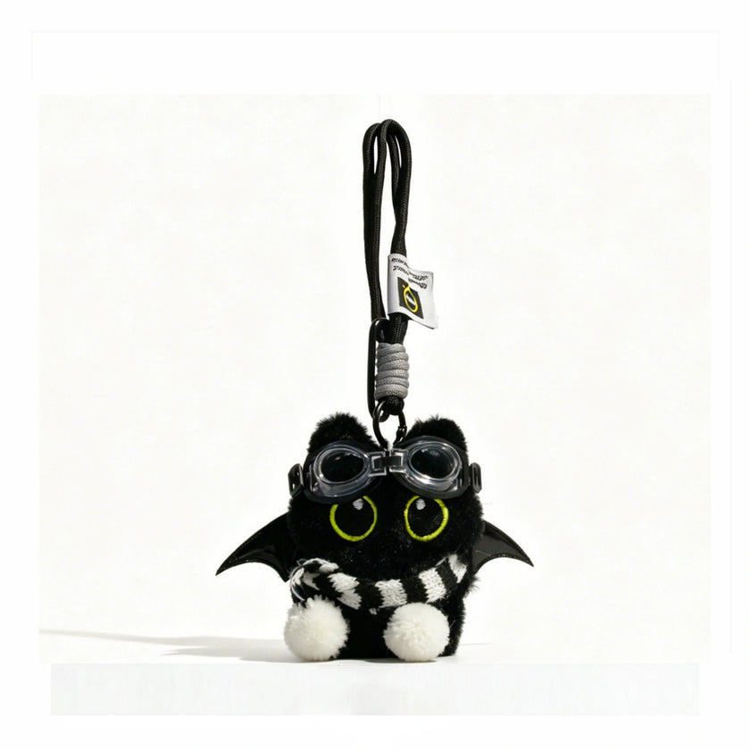 Close-up of a black plush bat-winged Yoyo keychain wearing goggles and a black-and-white striped scarf