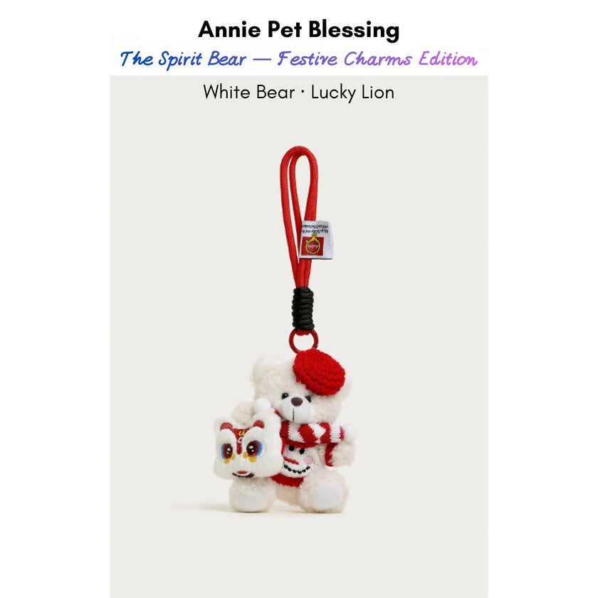 White plush Spirit Bear keychain wearing a red beret and scarf, holding a Lucky Lion charm