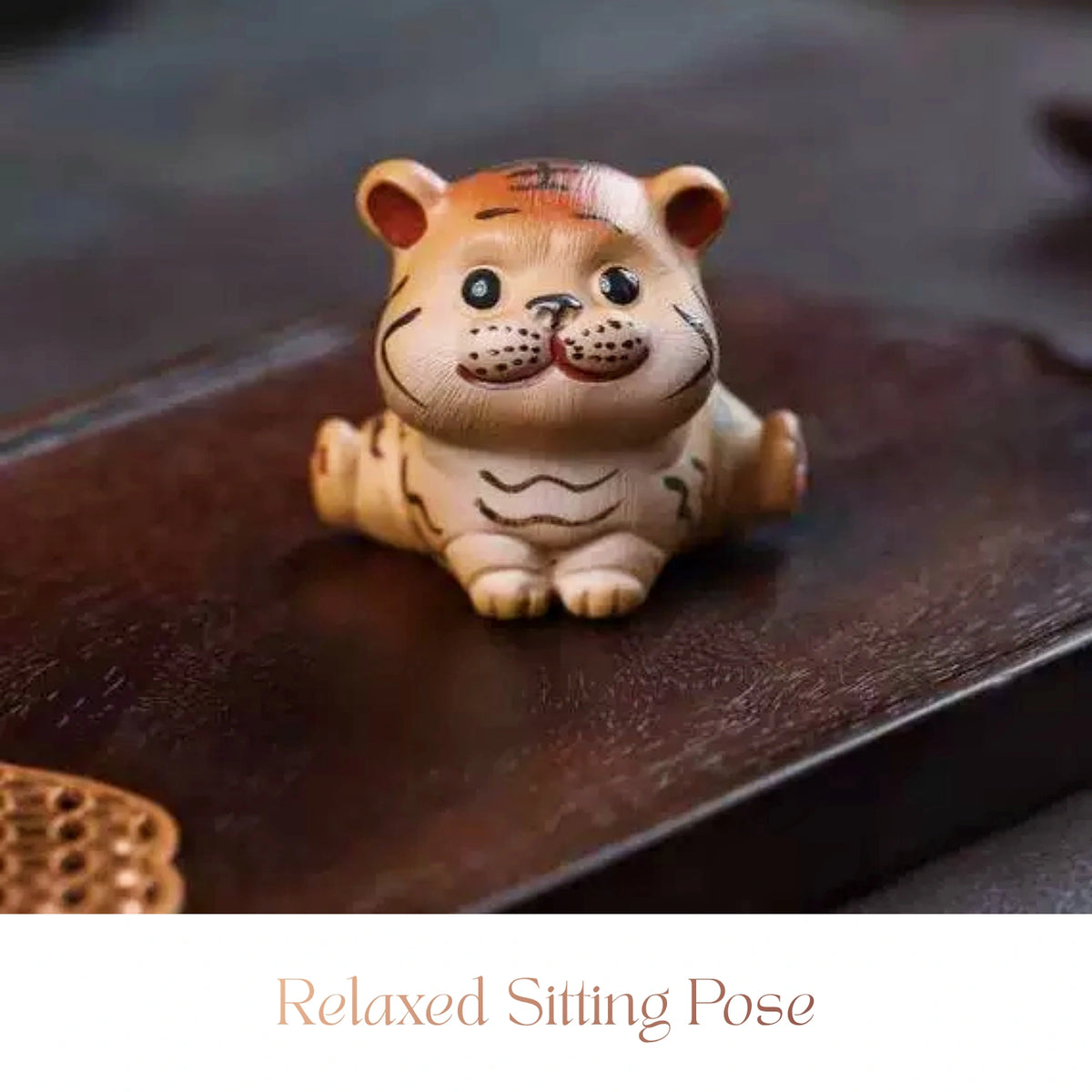 Close-up of a ceramic Spirit Tiger cub figurine sitting upright with a smiling expression
