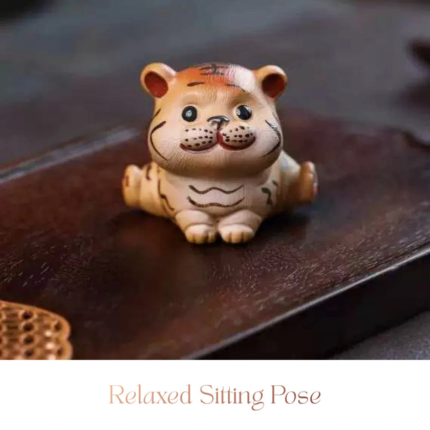 Close-up of a ceramic Spirit Tiger cub figurine sitting upright with a smiling expression