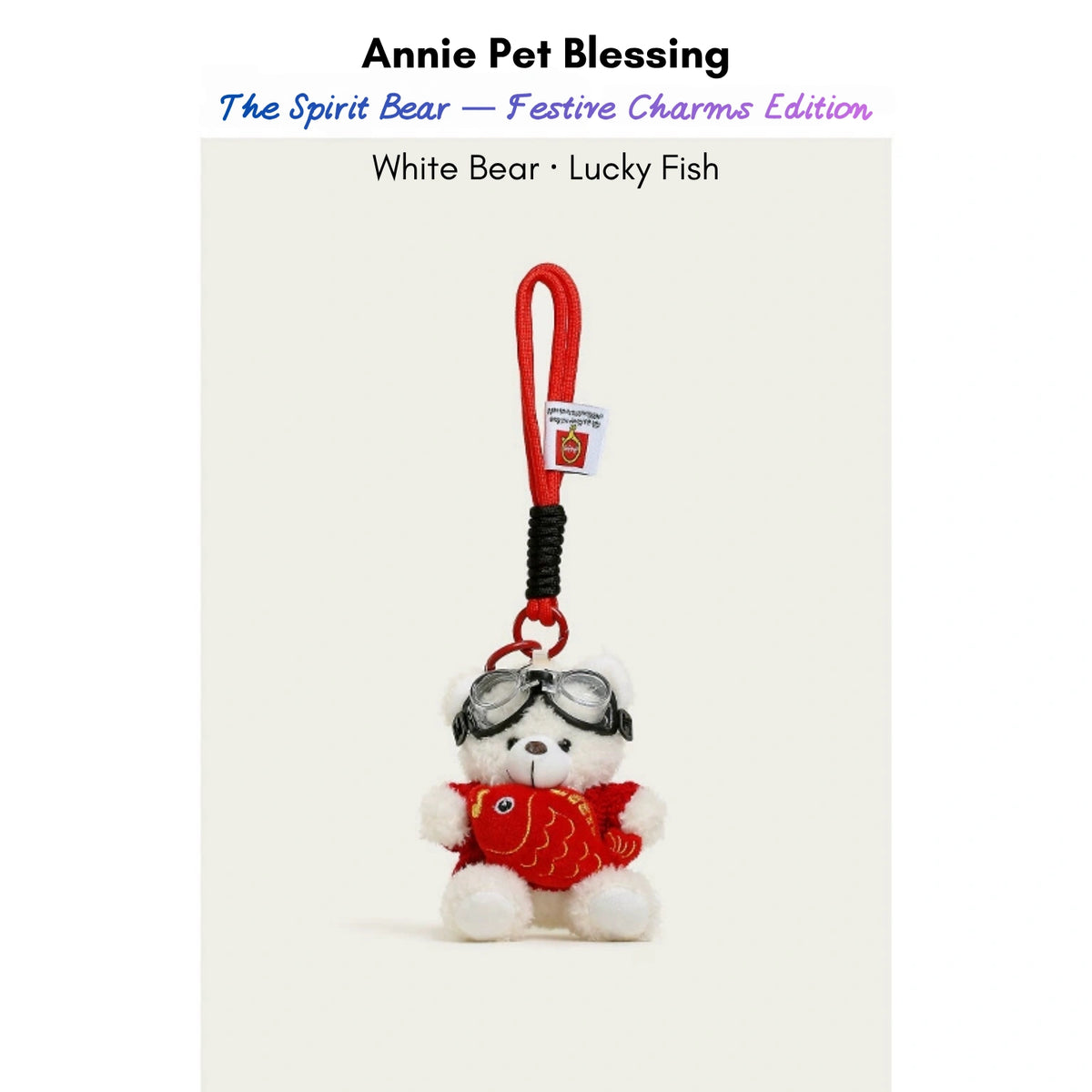 White plush Spirit Bear keychain wearing goggles and a red sweater, holding a Lucky Fish charm