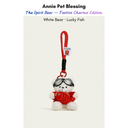 White plush Spirit Bear keychain wearing goggles and a red sweater, holding a Lucky Fish charm