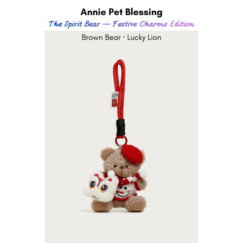 Brown plush Spirit Bear keychain wearing a red beret and scarf, holding a Lucky Lion charm