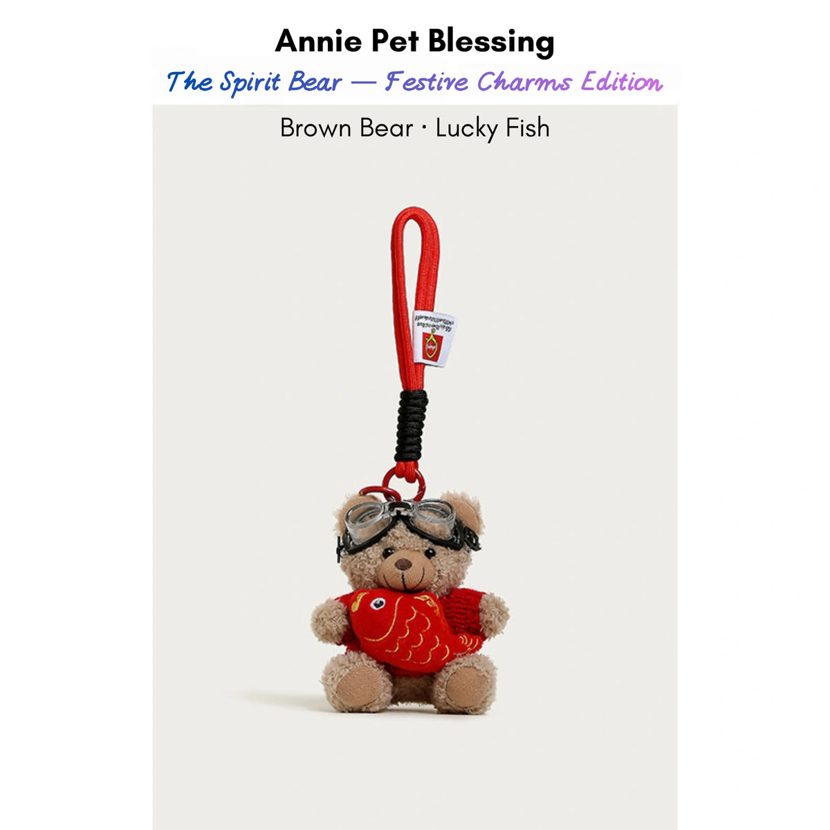 Brown plush Spirit Bear keychain wearing goggles and a red sweater, holding a Lucky Fish charm