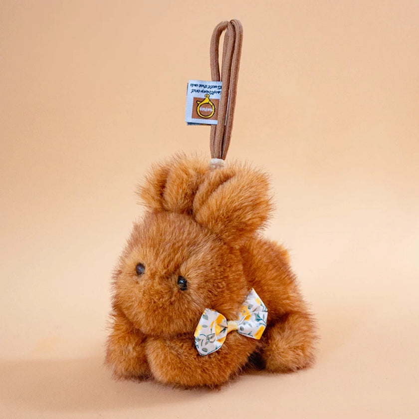 Brown plush Spirit Rabbit keychain with a folded ear, wearing a floral-print bow