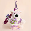 Westie plush keychain wearing a purple sweater, holding a crocheted lavender rose bouquet, lifestyle close-up