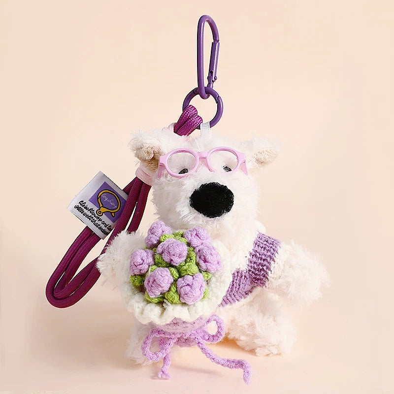 Westie plush keychain wearing a purple sweater, holding a crocheted lavender rose bouquet, lifestyle close-up
