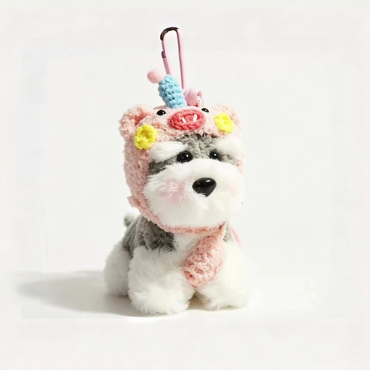 Grey-and-white plush Spirit Dog keychain wearing a pink knitted piglet hood with a crocheted unicorn horn