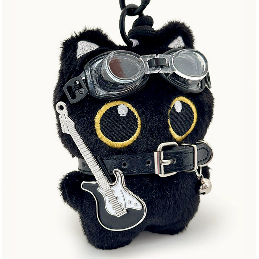 Close-up of a black plush Yoyo keychain wearing goggles, a studded collar, and a guitar-shaped charm