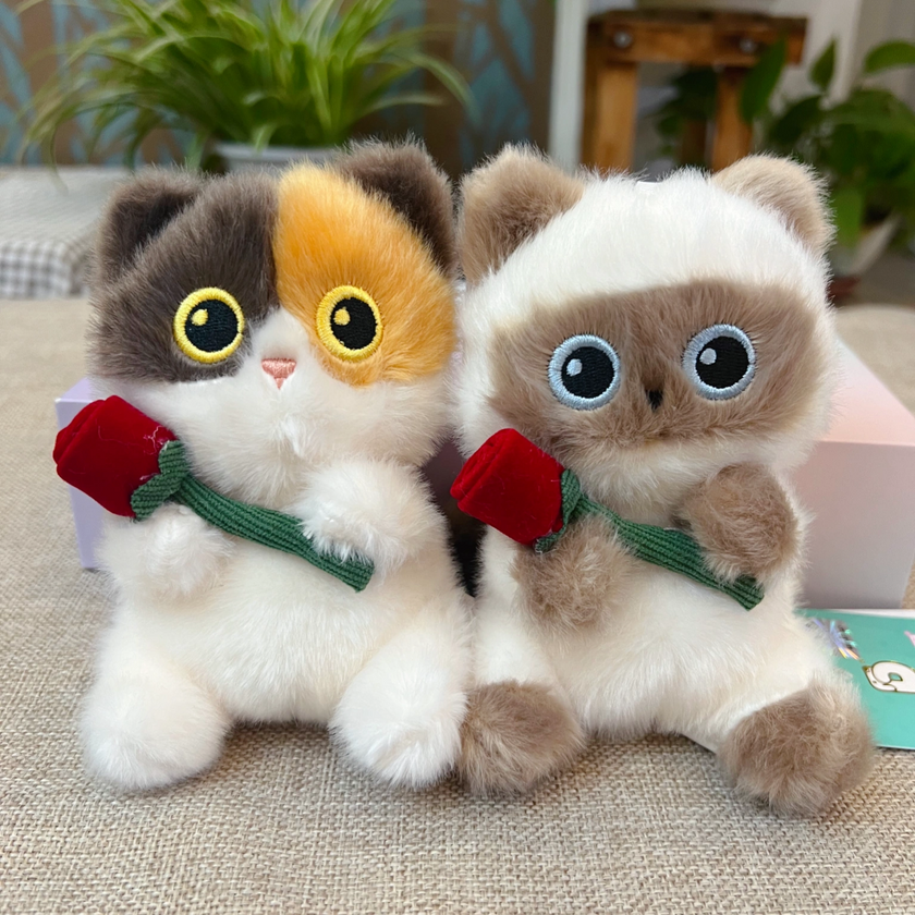 Calico and Siamese-style plush Spirit Cat keychains together, each holding a red rose