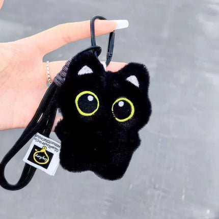 Hand holding a black plush Yoyo keychain in the classic design