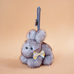 Gray plush Spirit Rabbit keychain wearing a yellow floral-print bow, front-facing
