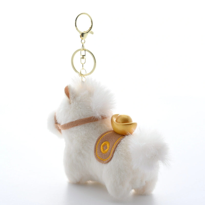 Close-up rear view of a white plush Heavenly Steed horse keychain with a gold-embroidered saddle blanket