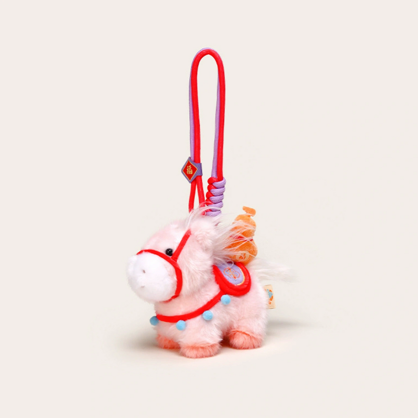 Close-up of a white plush Heavenly Steed horse keychain with an orange bridle and red-topped charm