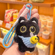 Hand holding a black plush Yoyo keychain with a light blue crocheted bee pouch in a shop setting