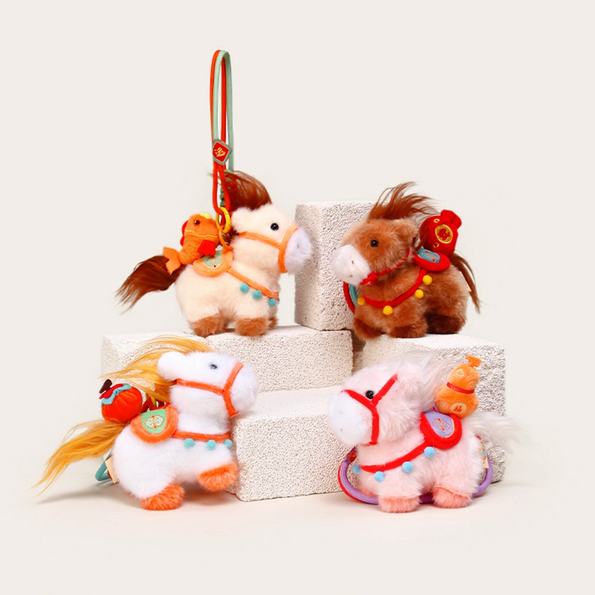 Close-up of a pink plush Heavenly Steed horse keychain with a red bridle and lavender saddle patch