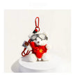 White plush Spirit Bear keychain wearing goggles and holding a red charm, on a white pedestal