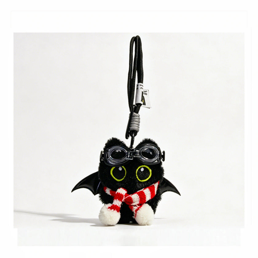Close-up of a black plush bat-winged Yoyo keychain wearing goggles and a red-and-white striped scarf