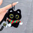 Hand holding a black plush Yoyo keychain wearing a red-and-green striped knitted scarf