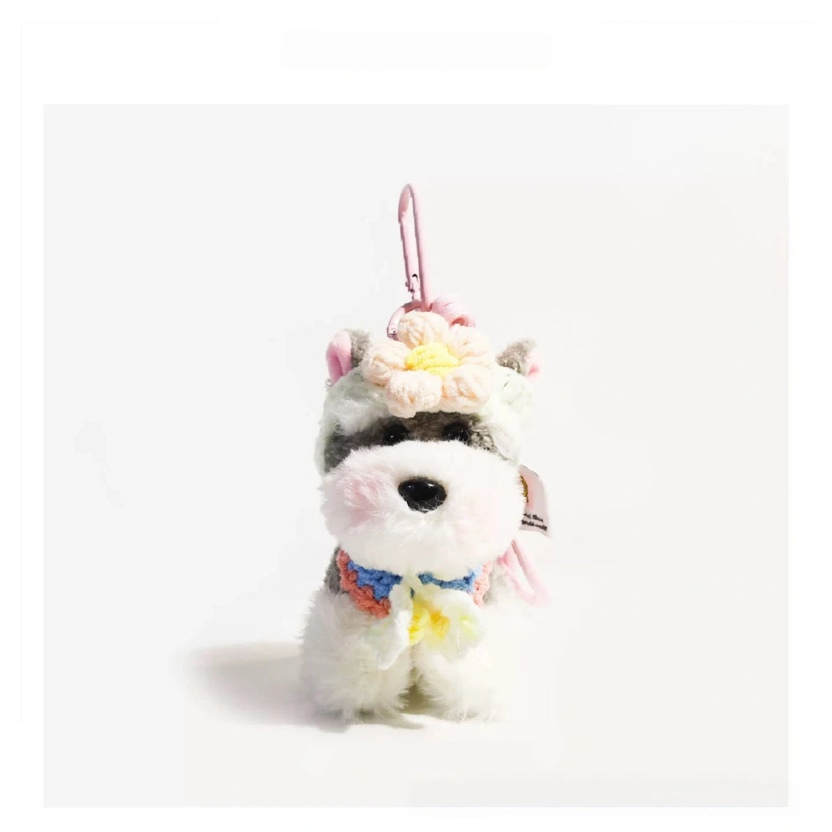 Grey-and-white plush Spirit Dog keychain wearing a peach crocheted flower headpiece and bib