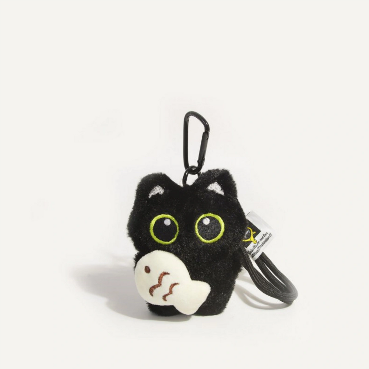 Close-up of a black plush Yoyo keychain holding the cream Cozy Fish charm with wave embroidery