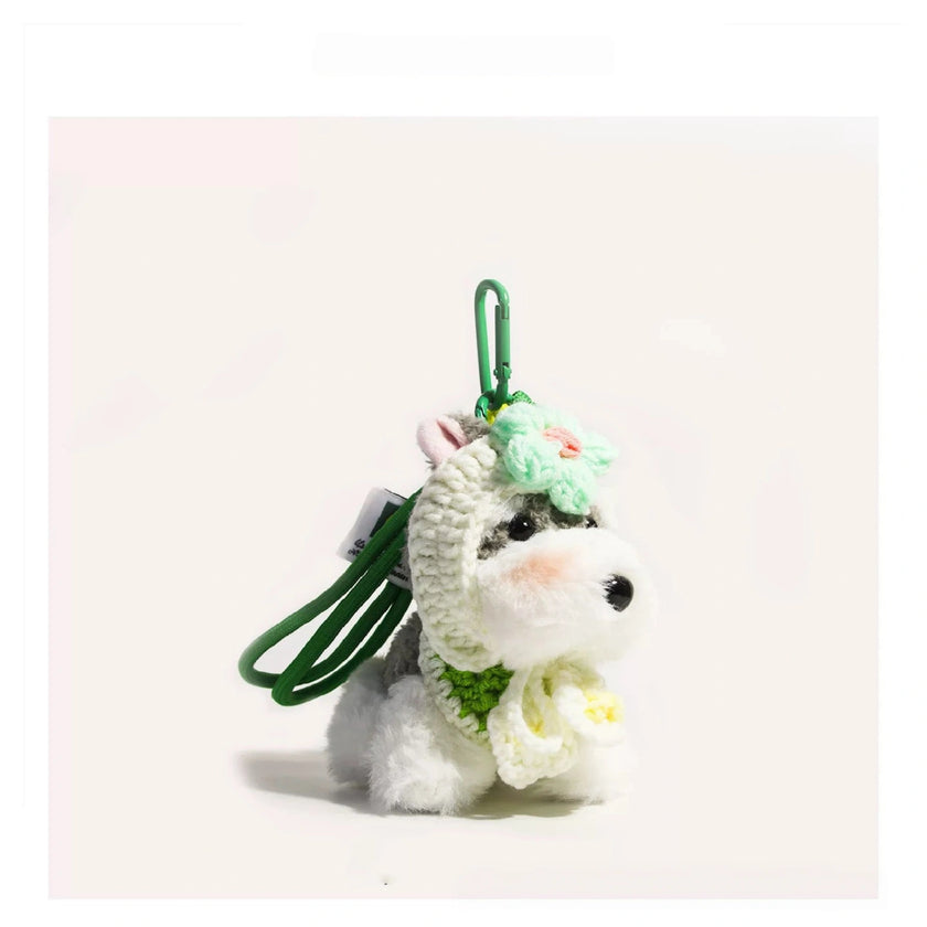 Close-up of a grey-and-white plush Spirit Dog keychain wearing a mint-green crocheted flower headpiece