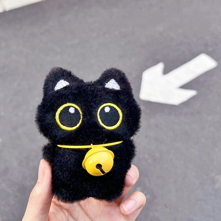 Hand holding a black plush Yoyo keychain with a yellow bell collar