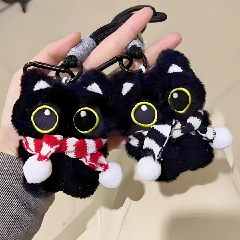 Two black plush Yoyo keychains held together, each wearing a different striped knitted scarf