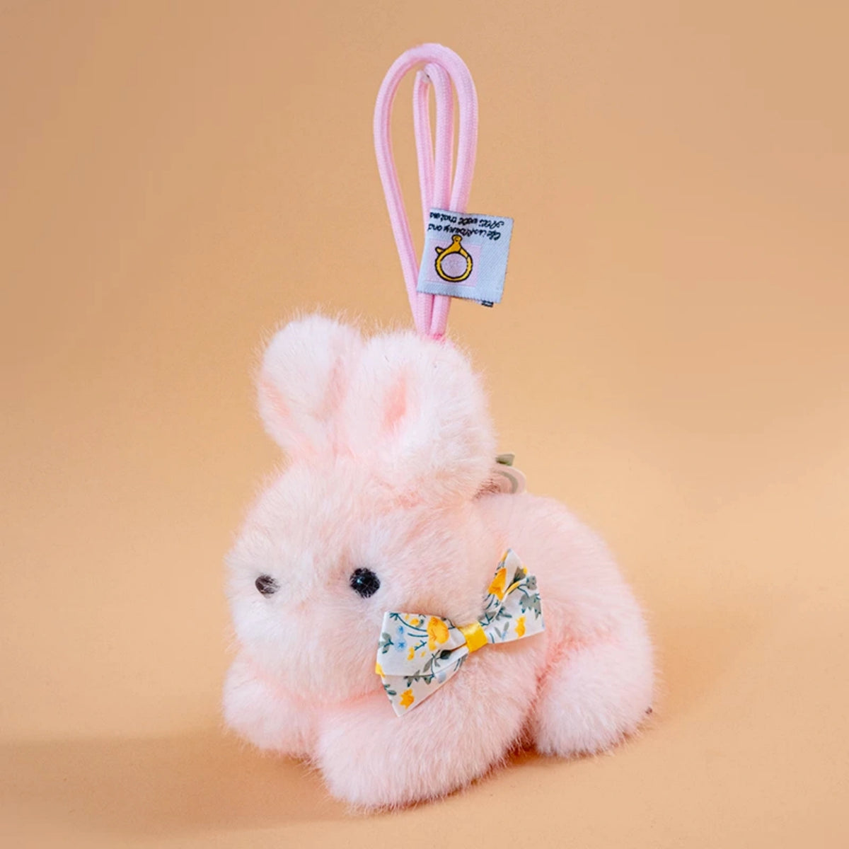 Pink plush Spirit Rabbit keychain wearing a yellow floral-print bow