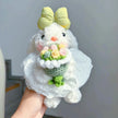 White plush Spirit Rabbit keychain wearing a lace dress, held in hand, holding a pink and yellow rose bouquet