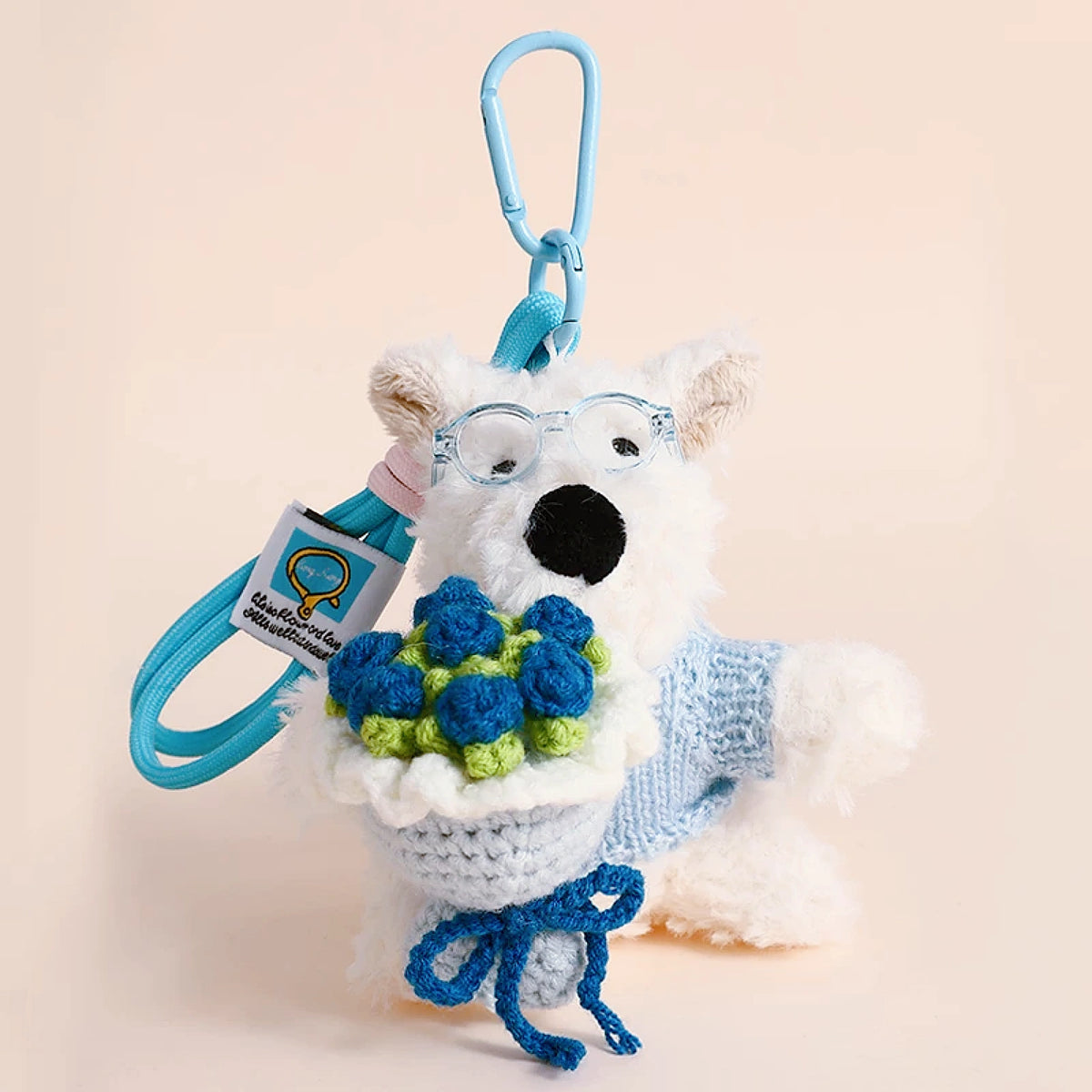 Westie plush keychain wearing a blue sweater, holding a crocheted blue rose bouquet, lifestyle close-up
