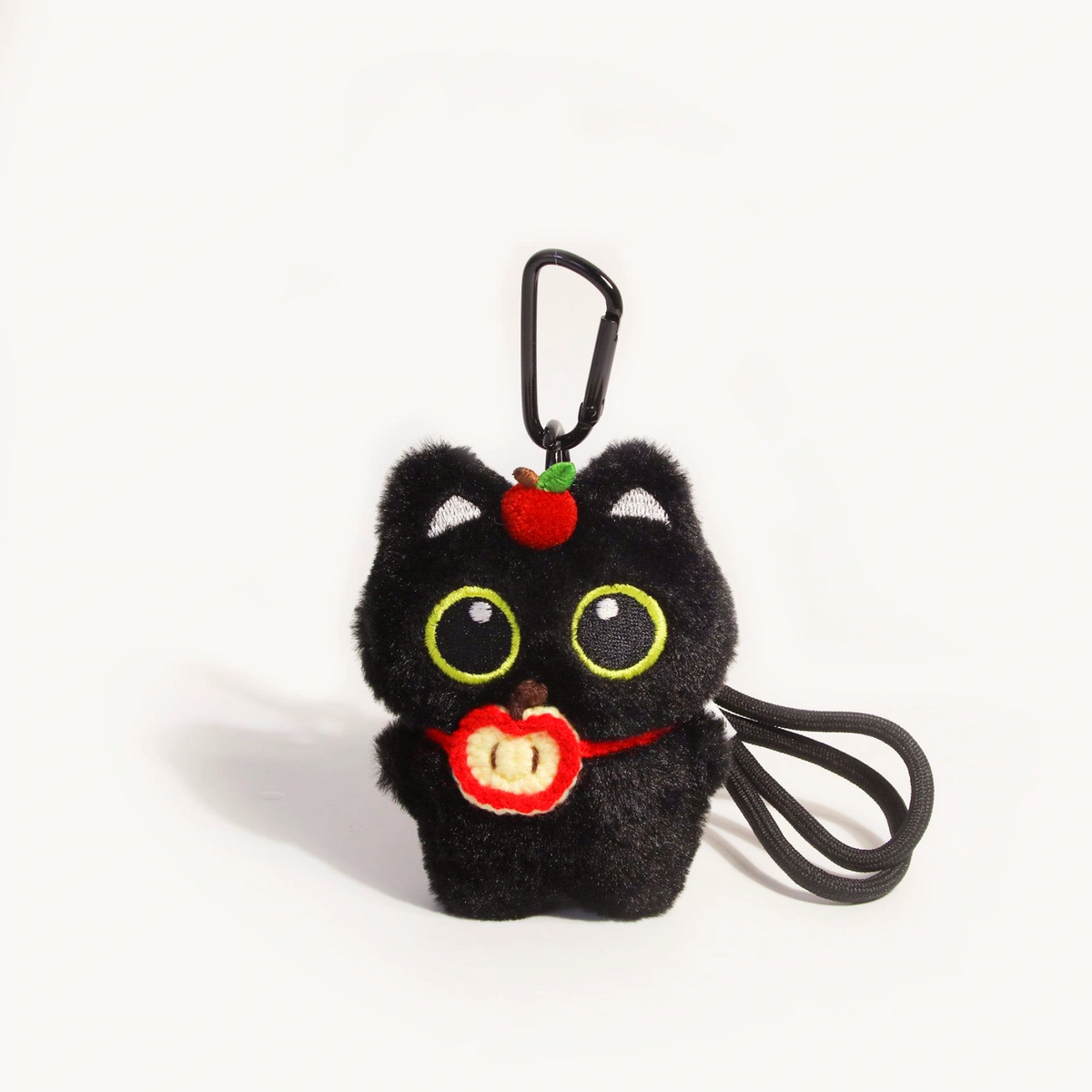 Close-up of a black plush Yoyo keychain holding a red apple slice charm
