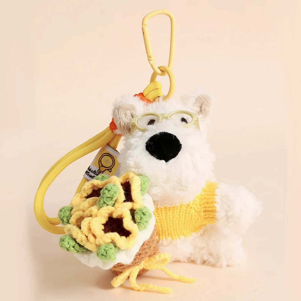 Westie plush keychain wearing a yellow sweater, holding a crocheted sunflower bouquet, lifestyle close-up
