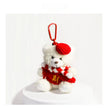 White plush Spirit Bear keychain wearing a red beret and scarf, on a white pedestal