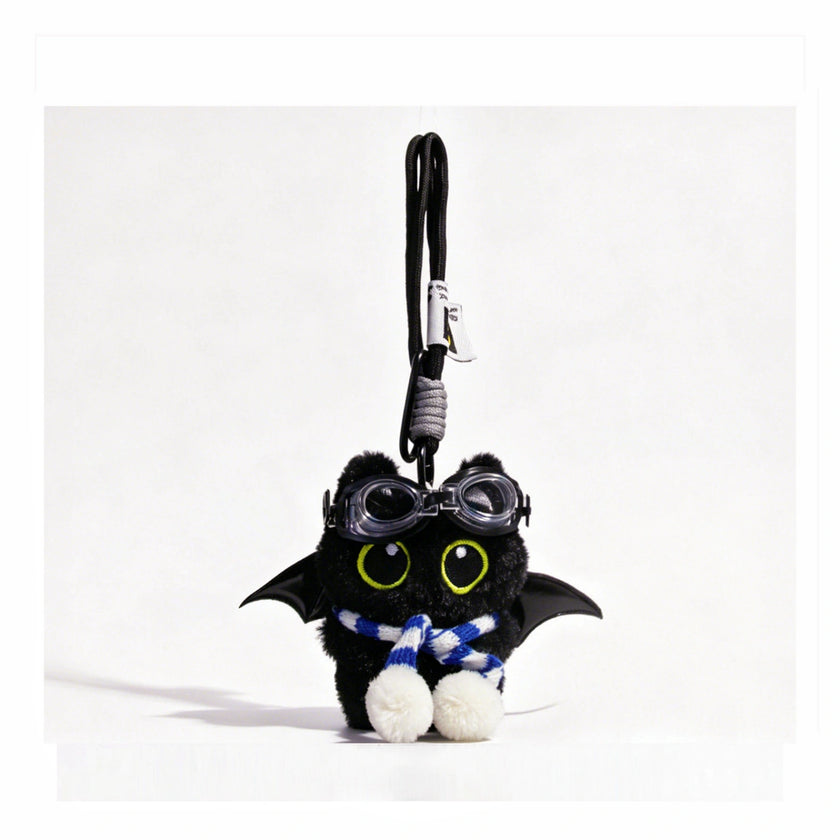 Close-up of a black plush bat-winged Yoyo keychain wearing goggles and a blue-and-white striped scarf
