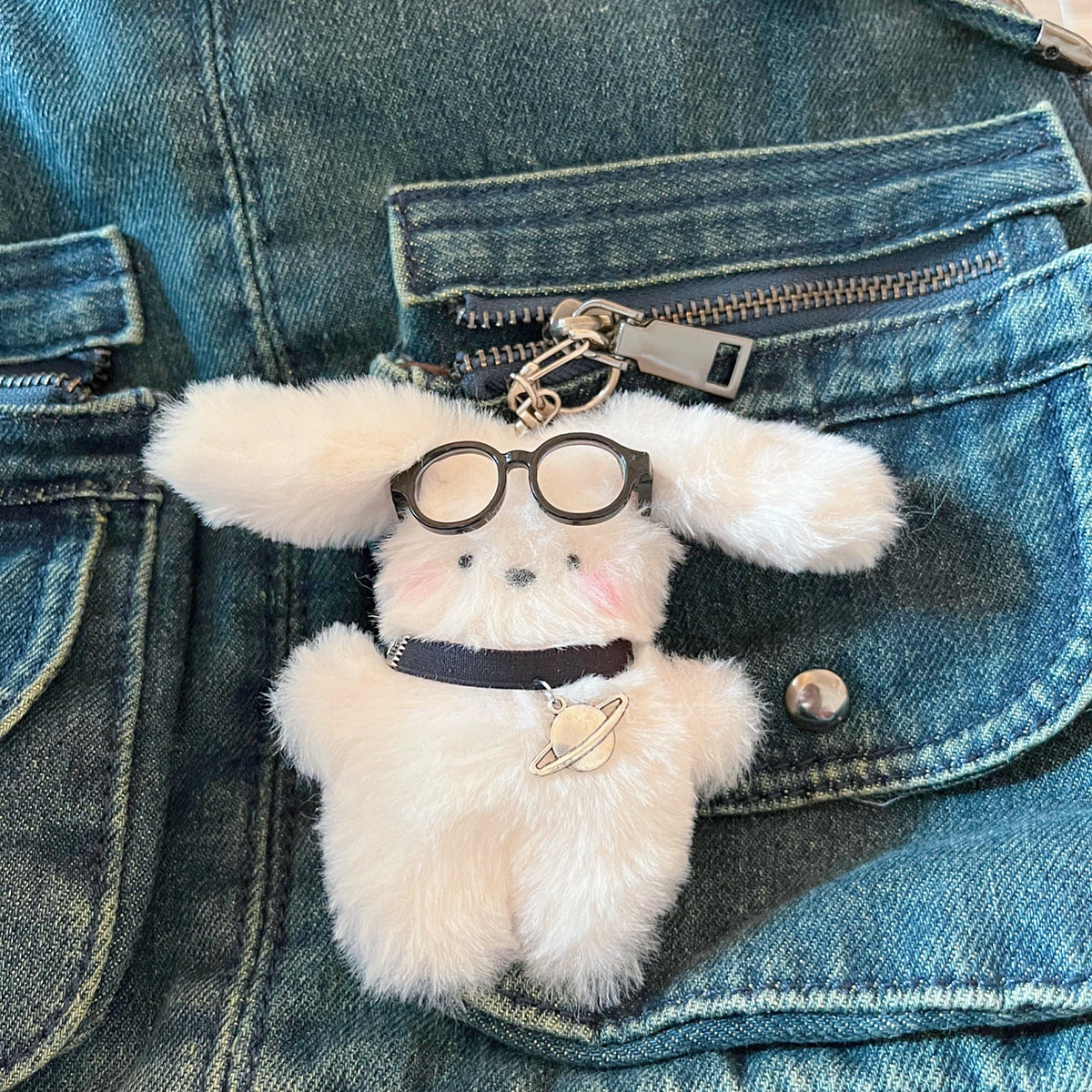 White fluffy plush charm keychain with a planet charm, clipped to a denim jacket pocket