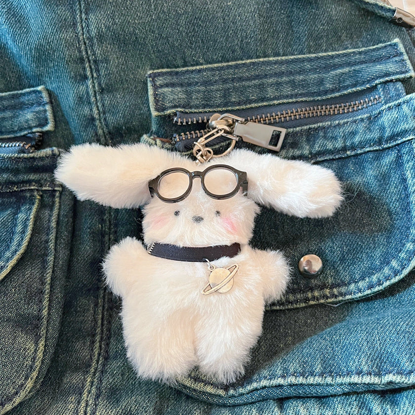 White fluffy plush charm keychain with a planet charm, clipped to a denim jacket pocket