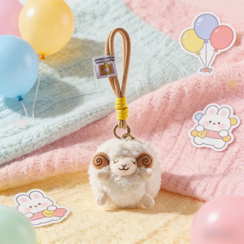 White plush Spirit Sheep keychain resting on a pastel blanket with balloons and stickers