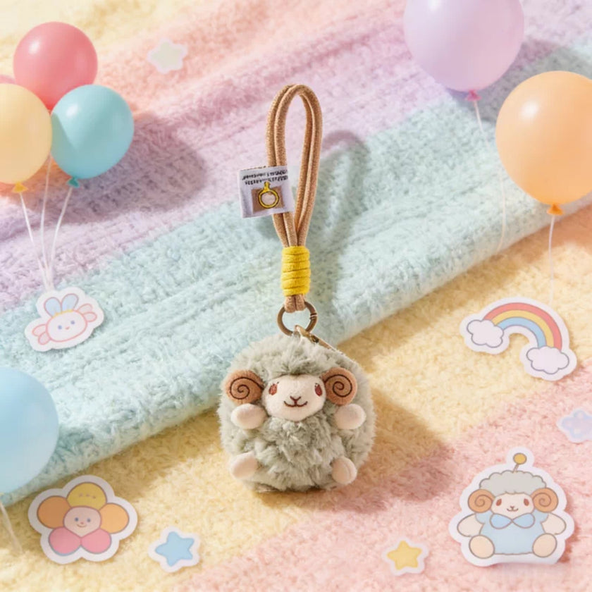 Sage green plush Spirit Sheep keychain on a pastel blanket with balloons and stickers