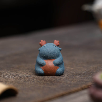 Close-up of a ceramic Spirit Dragon figurine in blue with reddish-brown antlers and a brown belly patch